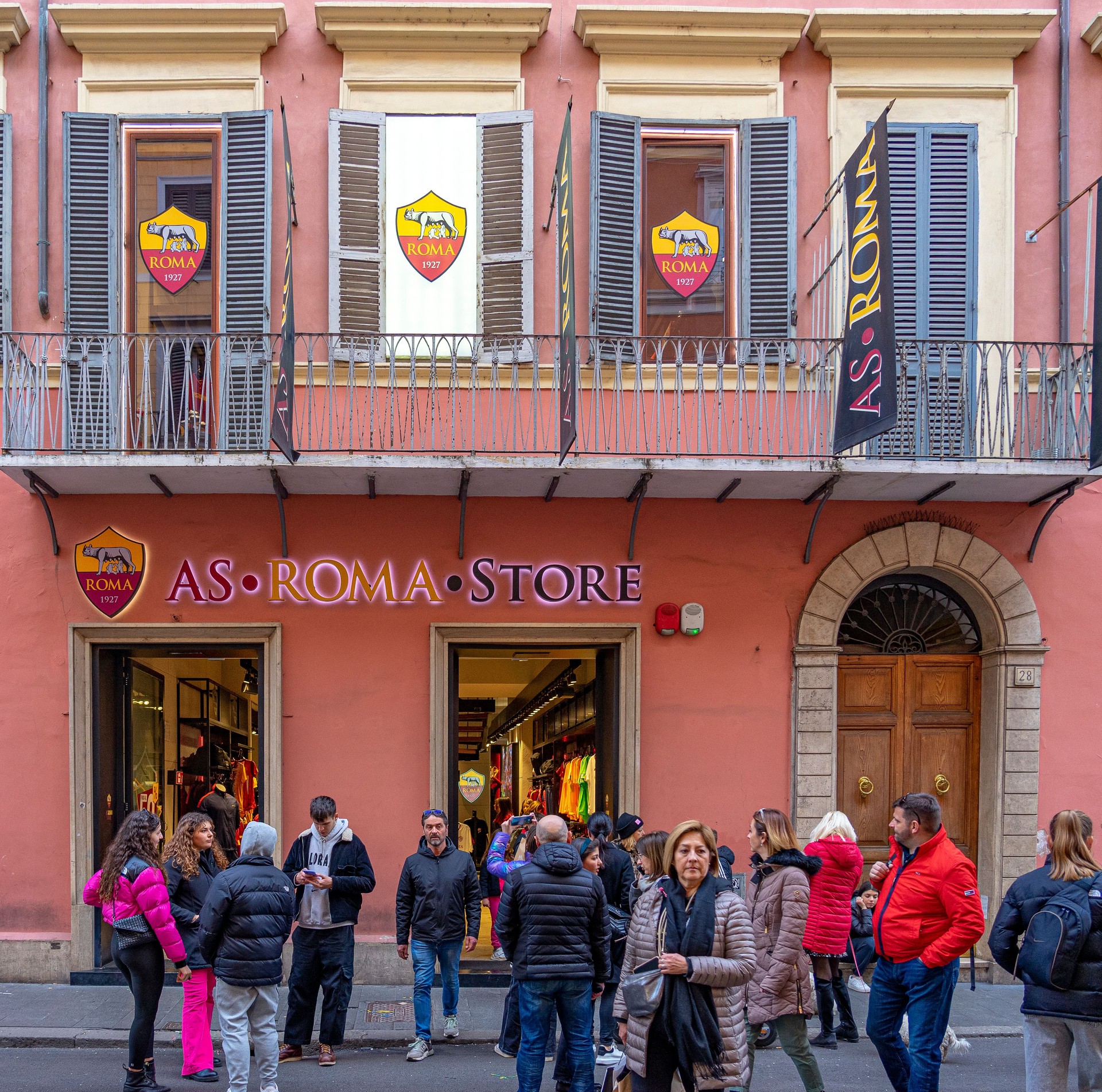 Roma football club shop door with ground floor and first floor with pink painted wall in Rome city center.