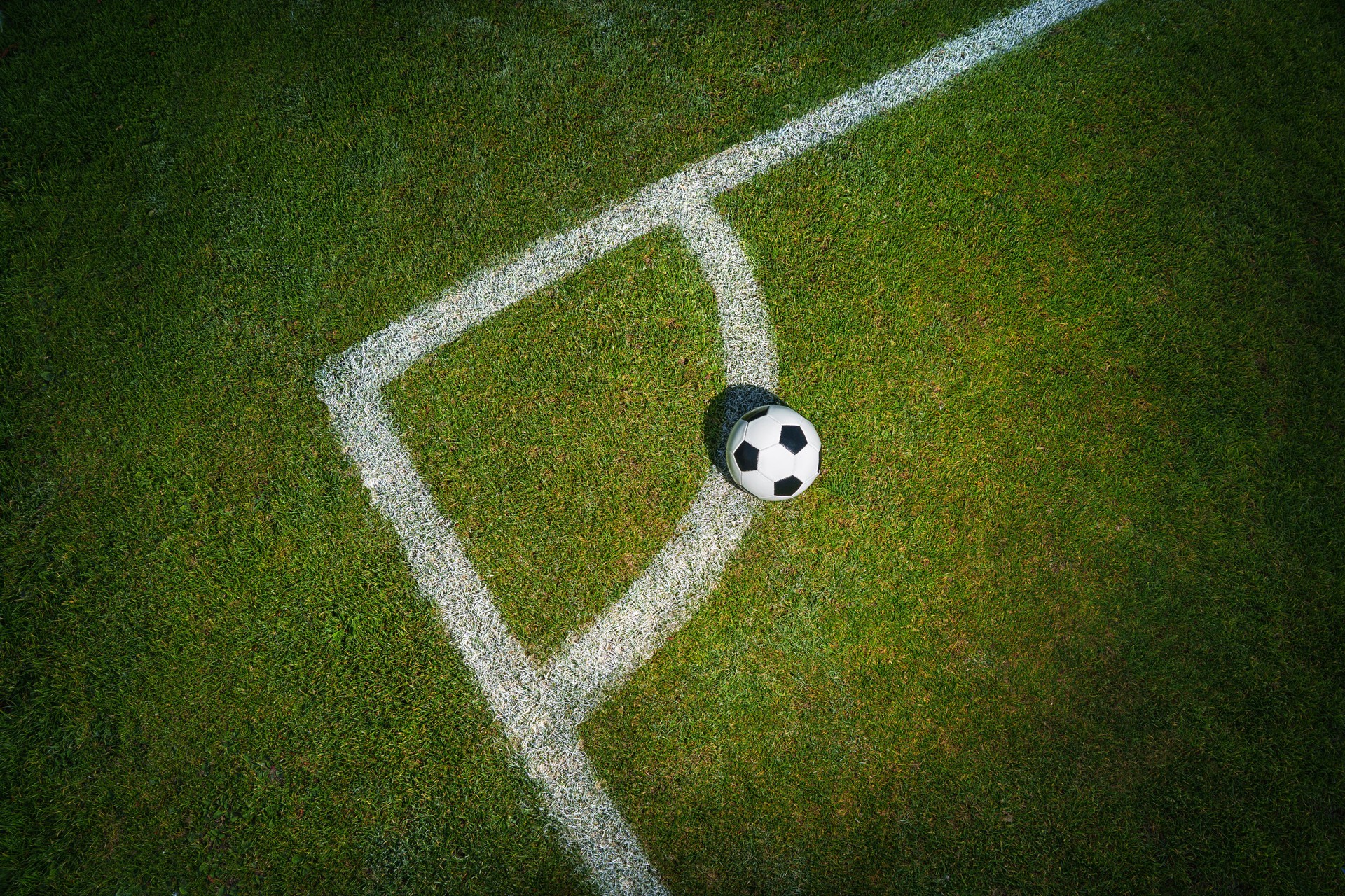 Soccer ball on sports textured green field - corner